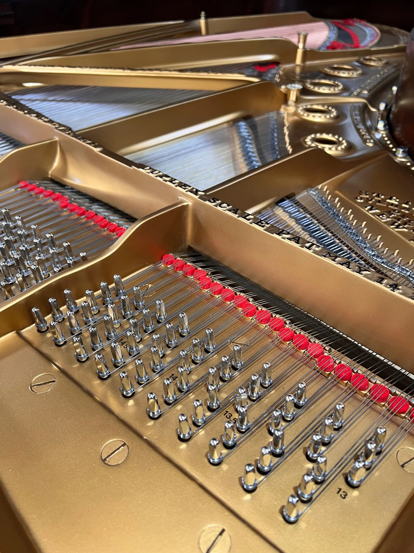The gilded frame and strings of a grand piano in the Leverett workshop